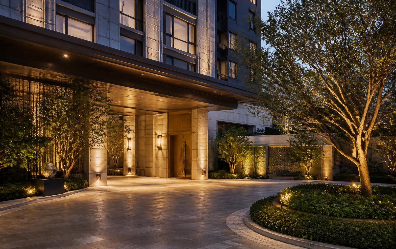 Softly lit residential arrival court with landscaped surrounds at dusk