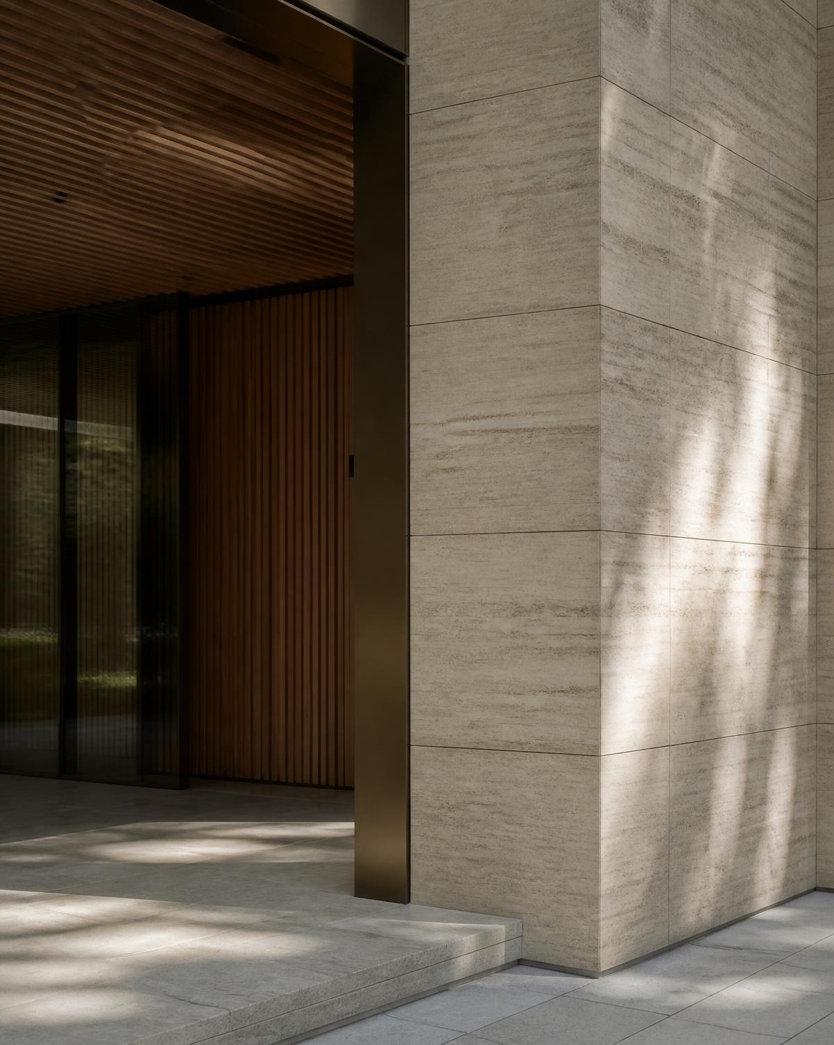 Architectural detail of a residential entrance in travertine and bronze